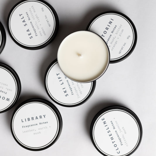 Discovery Flight: Salt + Ember 3 oz travel tin candles in several scents, one open