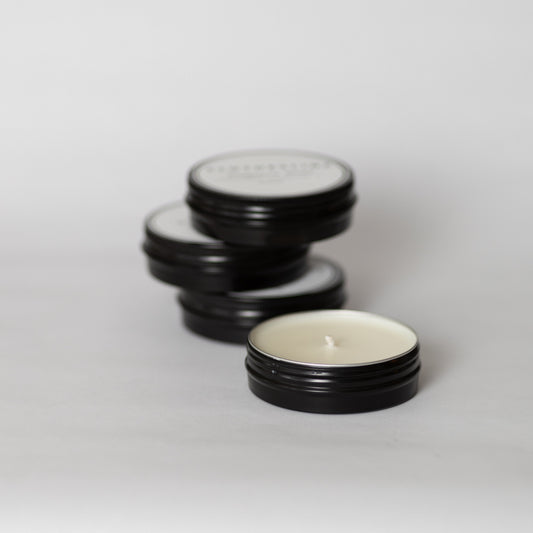 Salt + Ember 3 oz travel tin soy candles, one open to show the wax